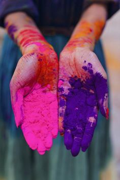 two hands covered in colorful powder holding each other