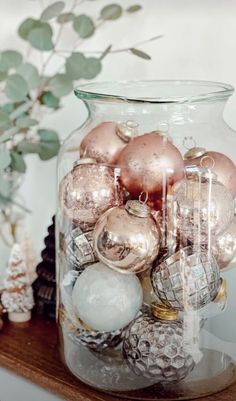 a glass jar filled with ornaments on top of a table