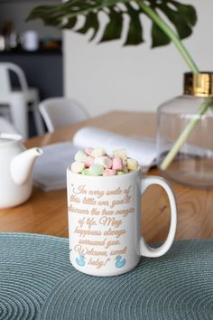 a coffee mug filled with marshmallows on top of a table