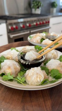 two plates with dumplings and chopsticks sitting on a table in a kitchen