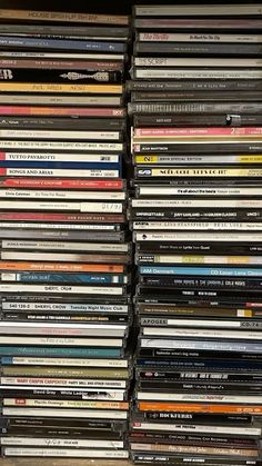 a large stack of cds sitting on top of a wooden shelf next to a wall