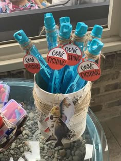 a glass table topped with lots of blue pens and paper stick holders on top of rocks