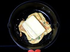 an omelet is being cooked in a skillet on the stove with a red spatula