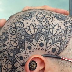 a man with a tattoo on his head has ear piercings attached to his ears