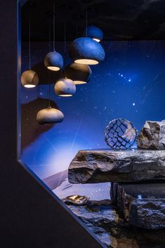 some lights are hanging from the ceiling above rocks and rock formations in a room with blue walls