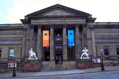 an old building with statues on the front and side walk up to it's entrance