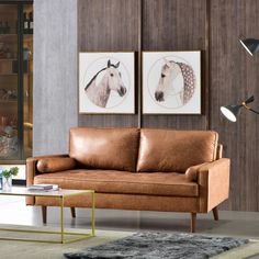 a brown leather couch sitting in a living room next to a glass table and lamp