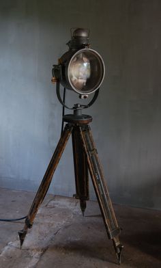 an old fashioned tripod with a light on it's legs and a cat in the lens