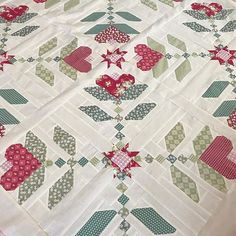 a quilted table topper with hearts and flowers on it