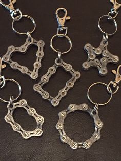 six metal chains are shown on a black surface with one keychain in the middle