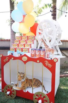 a tiger in a cart with balloons and candy on the ground next to some decorations