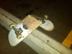 an upside down skateboard on the side of a wooden fence post at night time