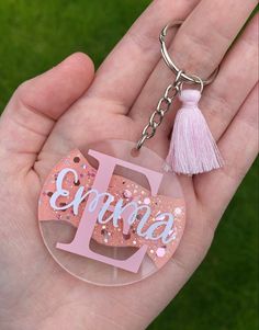 a person holding a keychain with the letter j on it and a tassel