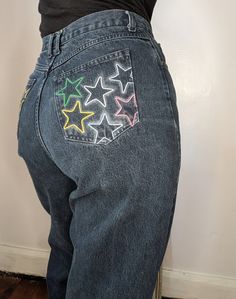 Sensible Slacks Original Reworked Rainbow Star Jeans. A pair of vintage dark wash high rise Crossroads jeans reworked with embroidered rainbow stars on the rear pockets. Black Straight Leg Pants With Star Print, Denim Blue Straight Leg Bottoms With Star Print, Straight Leg Bottoms With Star Print In Denim Blue, Straight Leg Denim Blue Bottoms With Star Print, Trendy Dark Wash Jeans With Star Print, Star Pocket Jeans, Embroidered Rainbow, Rainbow Stars, Pockets Pants