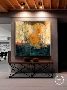 an abstract painting hangs on the wall above a coffee table in a modern living room