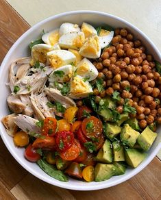 a white bowl filled with lots of different types of food on top of a wooden table