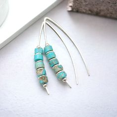 "Handmade Turquoise Threader Earrings. Perfectly suited for everyday boho vibes, these wishbone threaders feature vibrant turquoise jasper for a touch of eye-catching color that won't go unnoticed!  * Sterling Silver * Approximately 1.5\" long * Turquoise Jasper Heishi Beads * Sent in a Ribboned Gift Box with Polishing Cloth * Handmade in Montana  ----- OUR MATERIALS -----  *STERLING SILVER - Experience the elegance of Sterling Silver, a metal that combines versatility with a sophisticated look. Adjustable Turquoise Earrings With Ear Wire, Handmade Minimalist Turquoise Hoop Earrings, Turquoise Hoop Earrings As A Gift, Turquoise Hoop Earrings For Gift, Turquoise Dangle Hoop Earrings, Minimalist Turquoise Wire Wrapped Earrings, Turquoise Pierced Earrings, Silver Threader Earrings, Open Hoop Earrings