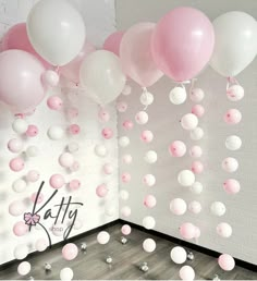 pink and white balloons floating from the ceiling in a room with grey wood flooring