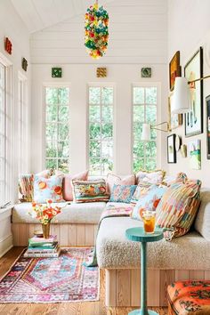 a living room filled with lots of furniture and pillows on top of a wooden floor