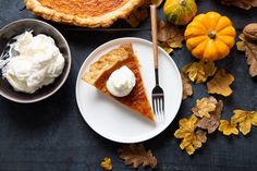 pumpkin pie and whipped cream on plates with autumn leaves around it, top view from above