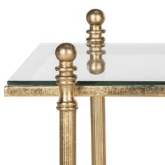 a glass and gold table with two candlesticks on each one side, against a white background