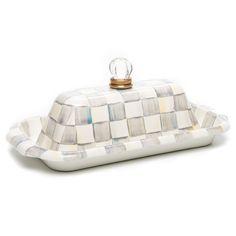 a white and blue checkered tray with a gold ring on the top, sitting on a white surface