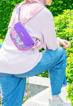 a woman sitting on some steps with a purple purse in her lap and looking at the ground