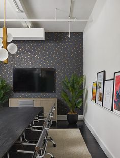 a conference room with black and white wallpaper, large desks and chairs in front of a flat screen tv