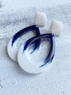 two white and blue earrings sitting on top of each other