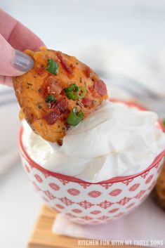 a person dipping some kind of food into a bowl with whipped cream and toppings