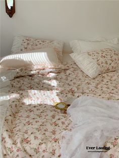 an unmade bed with pink flowers and white sheets