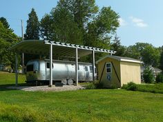 a silver bus parked in front of a small building on the side of a road