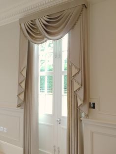 an open door with curtains hanging on it's sides and a window in the background