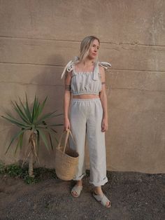 a woman standing next to a wall holding a basket