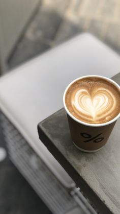 a cappuccino on a table with a heart shaped design in the foam