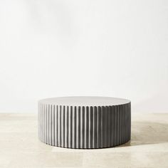 a round white table sitting on top of a hard wood floor next to a wall