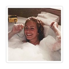 a woman in a bathtub with foam on her head and earphones attached to her ears