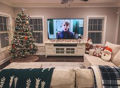 a living room filled with furniture and a christmas tree in front of a flat screen tv