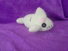 a white stuffed animal laying on top of a purple blanket