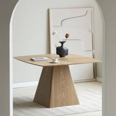 a table with a vase on it in front of an arch entrance to a living room