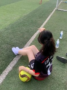 a woman sitting on the ground with a soccer ball