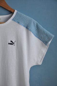 Vintage white and baby blue PUMA sports top, from the 1980s Summer 80s PUMA top with dolman short sleeves and long straight shape. The top features light blue terry cloth pieces on the shoulders, the rest is white! Has the brand's logo on the front Material - cotton and polyester, fabric is thick, not lightweight! Size - L Measurements (taken while top is lying flat, double armpit to armpit): Shoulders (undefined), measured from one sleeve's end to the other - 28.5 inches / 72.4 cm Armpit to Arm 90s Sports T-shirt For Summer, 90s Summer Sports T-shirt, Retro Sports T-shirt For Summer, White Sporty Top For Summer, Sporty White Top For Summer, White Retro Sports T-shirt, Retro White Sports T-shirt, Sporty White T-shirt For Summer, Vintage White Short Sleeve Top