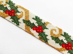 a cross stitch christmas ribbon with holly and bell decorations on white background, closeup