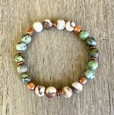 This AFRICAN TURQUOISE & OPALIZED PETRIFIED WOOD BRACELET combines so well with copper accent beads!  The African turquoise beads have  blue/green/black/brown variations and the opalized petrified wood beads are white/light brown/dark brown in color.  The gemstone beads are 8mm in size.  This combination works well with so many outfits and would be perfect to stack with your other bracelets or simply worn alone. A beautiful matching necklace is also available, sold separately. Jewelry items arri African Turquoise Bracelet, Brown Gemstone, Wood Bracelet, African Turquoise, Mala Necklace, Petrified Wood, Matching Necklaces, Turquoise Beads, Stone Bracelet