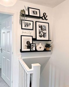 there are pictures and frames on the wall above the bannister in this entryway