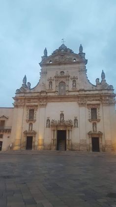 an old building with many windows and statues on it's front facade at dusk