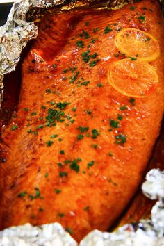 the fish is covered in tin foil and garnished with orange slices, parsley