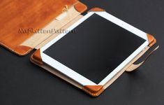 an ipad case sitting open on top of a black table next to a white tablet