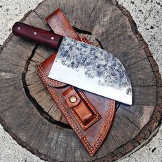 a large knife sitting on top of a piece of wood next to a knife sheath