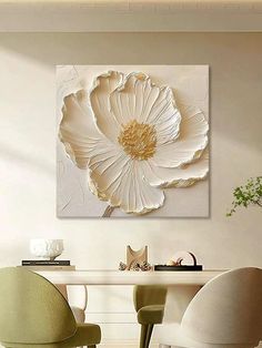 a dining room table with chairs and a large white flower on the wall above it